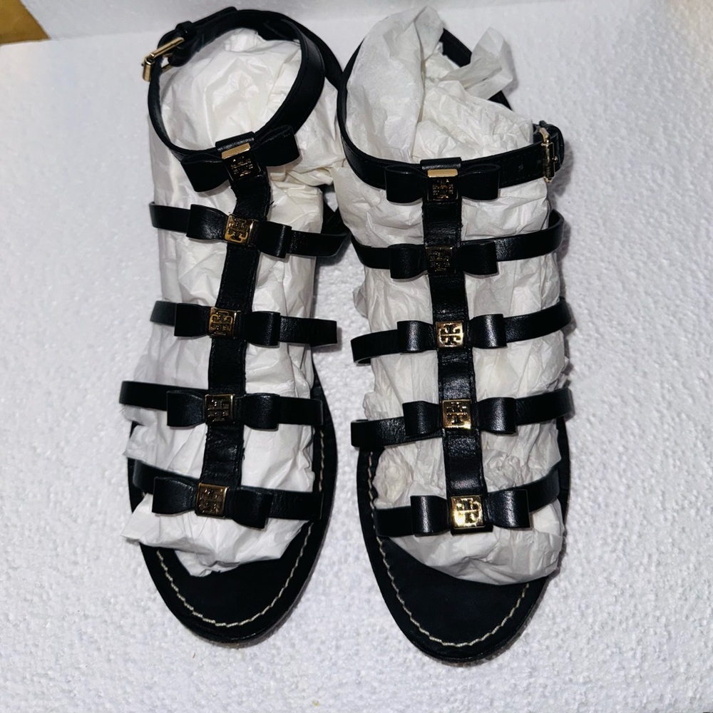 Tory Burch Kira black leather gladiator sandals with gold-tone logo bows.